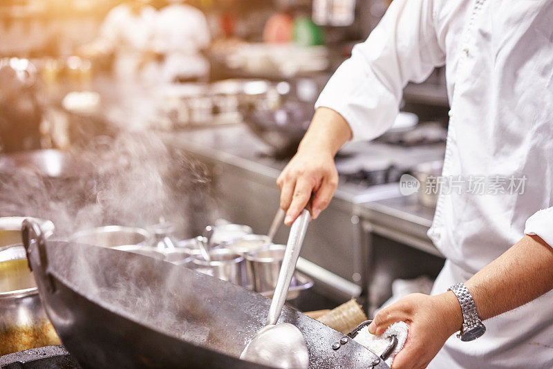 Chef in restaurant kitchen at stove with pan